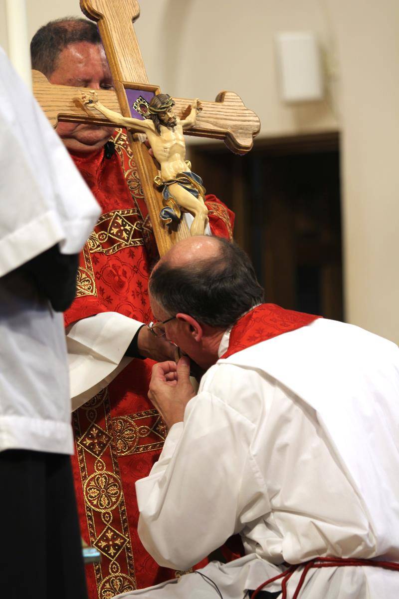 Bishop Peter Jugis kisses a crucifix containing a relic of the True Cross during Good Friday’s Veneration of the Cross service at St. Patrick Cathedral in Charlotte. (SueAnn Howell | Catholic News Herald)