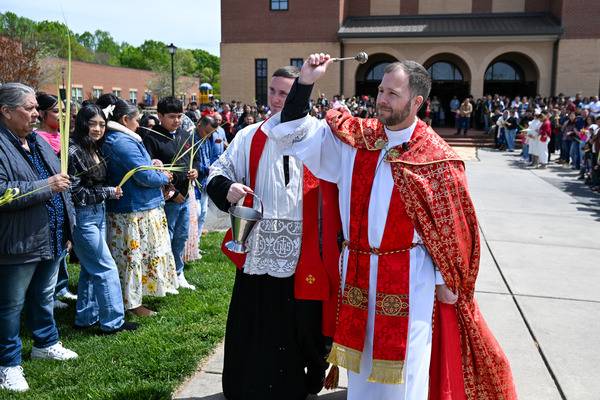 Father John Eckert blesses the people holding palms at the start of Palm Sunday Mass at Sacred Heart Church in Salisbury. (Troy C. Hull)