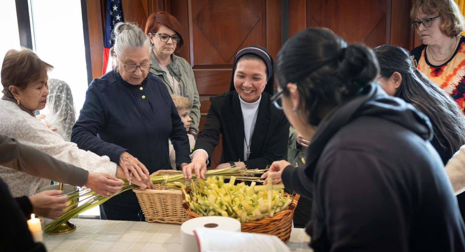 Sister Regina Ladoing, OP, helps parishioners as they take the blessed palms. (Edward Chaplinsky Jr.)